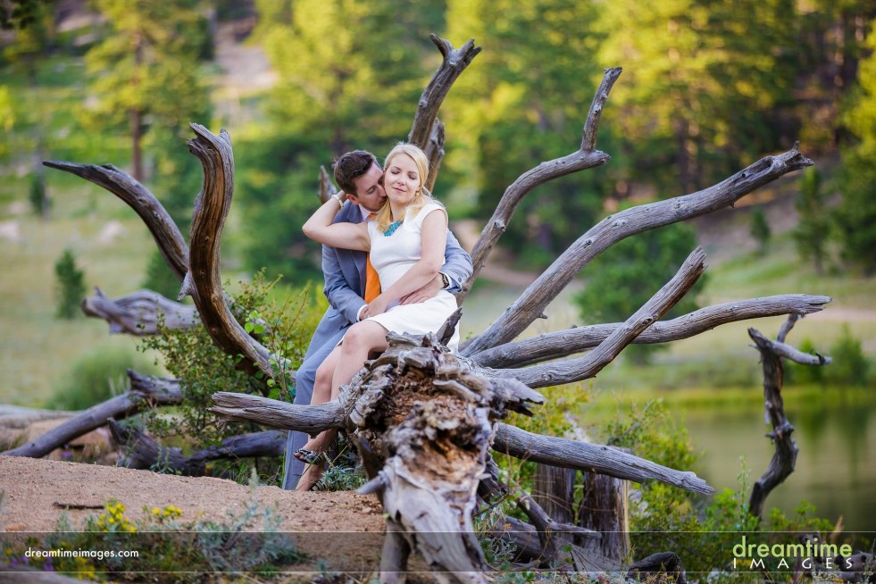 A couple kiss on a tree on the shore of a lake in Colorado