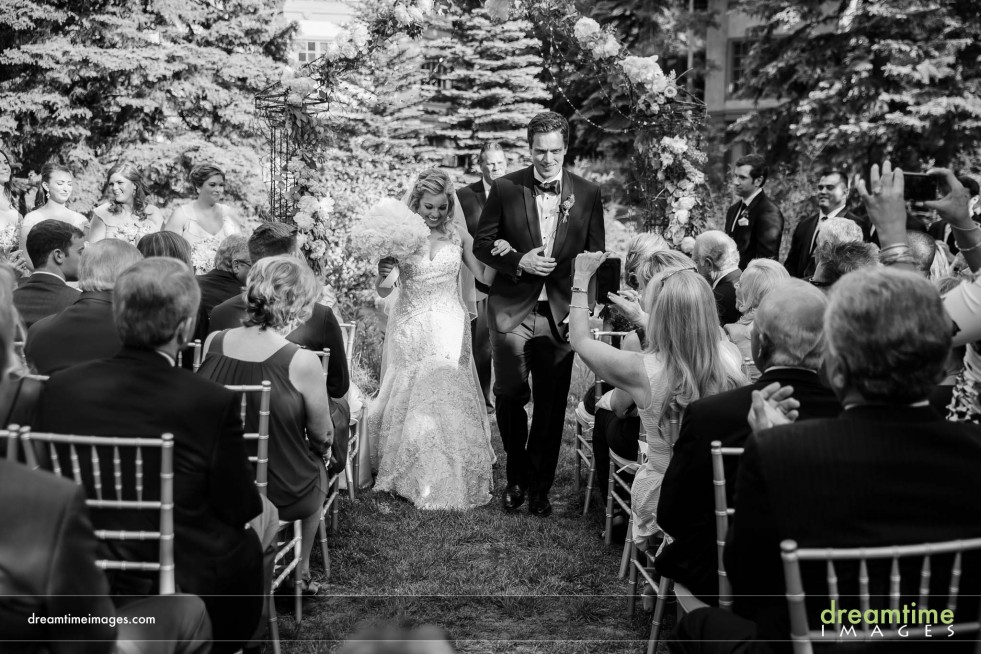 A bride and groom walk down the aisle in the garden at the Sonnenalp Pool Deck